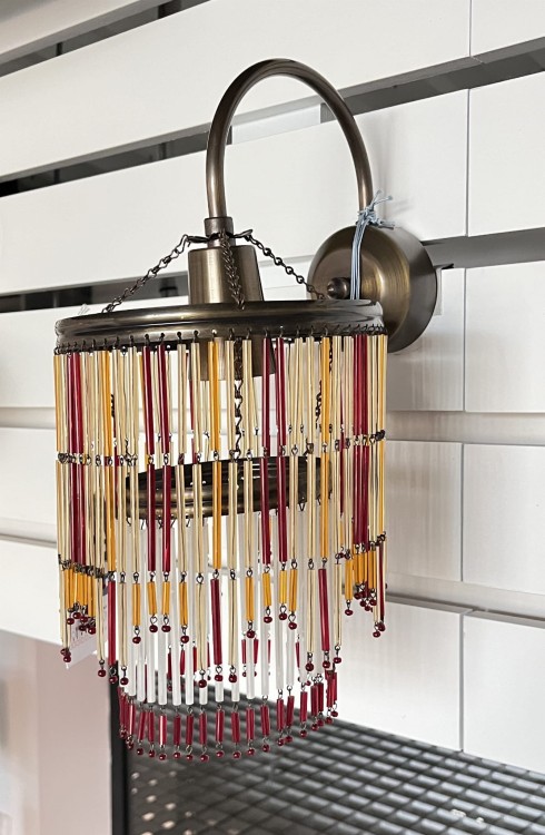 Kinkiet z metalowym korpusem w kolorze patynowym i kloszem z kolorowymi szklanymi wiszącymi ozdobami tworzącymi klosz